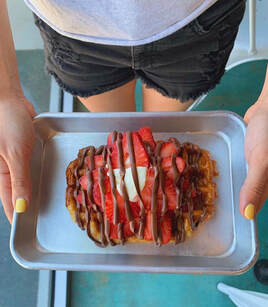 Me holding a waffle on a tray with strawberries and nutella drizzled on the top