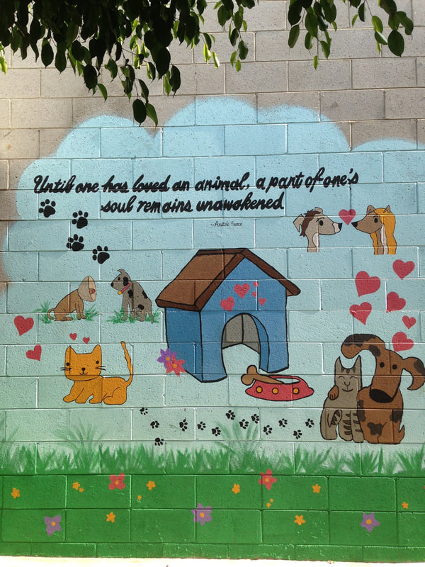 A mural of dogs and cats with a pet house in the middle with the saying, "Until one has loved an animal, a part of one's soul remains unawakened." 